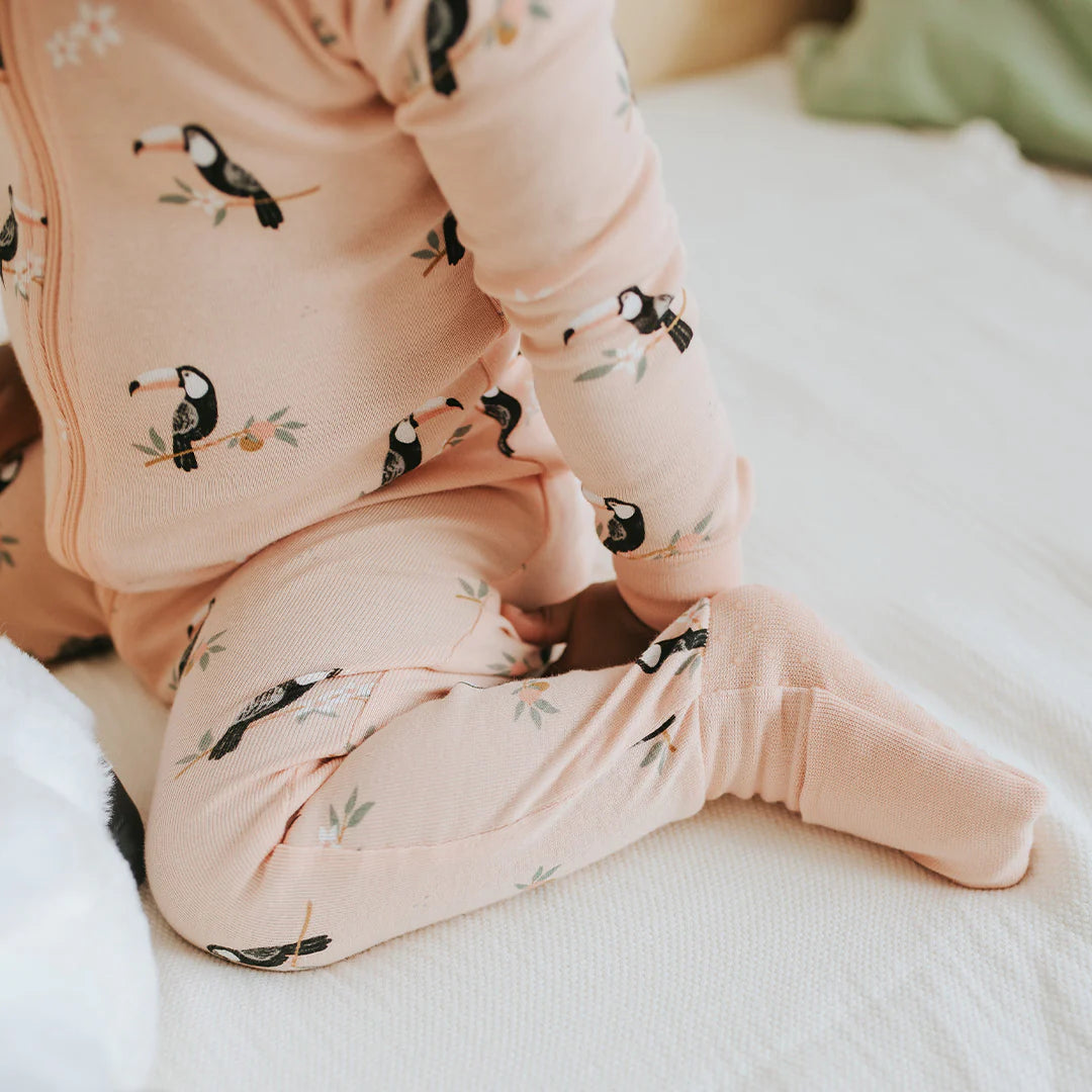Baby in papaya pink organic cotton sleeper with fold-over feet Petit Lem