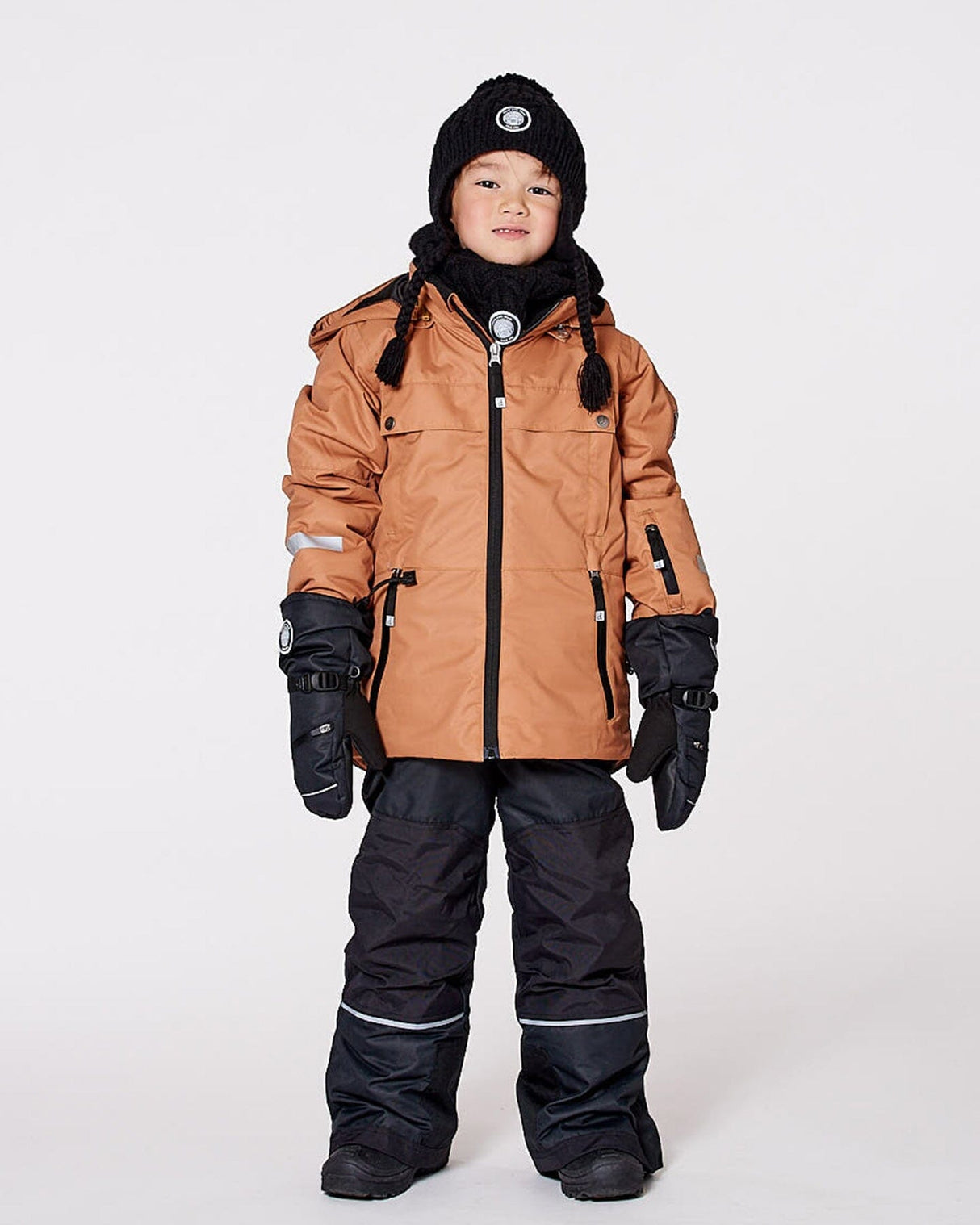 Child wearing brown & black Teknik snowsuit set – front on snow