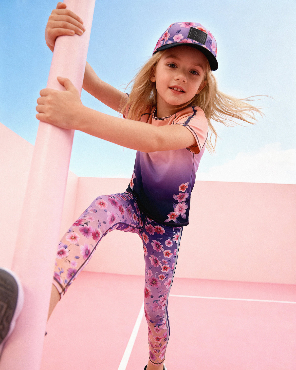 Child wearing the Deux par Deux floral gradient athletic leggings with a matching cap while climbing