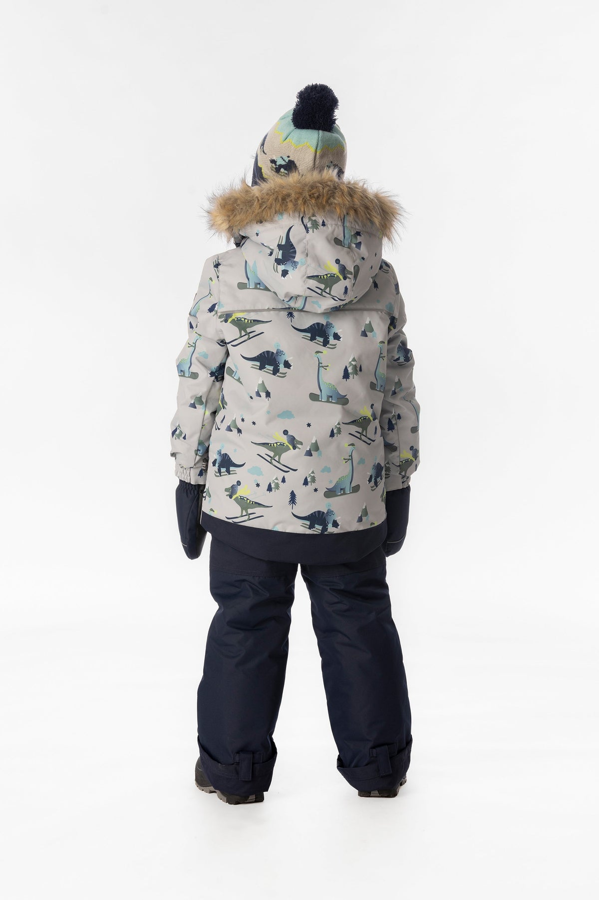 Child wearing the Deux par Deux DISCOVER snowsuit in grey skiing dinosaur print, lookbook view 3