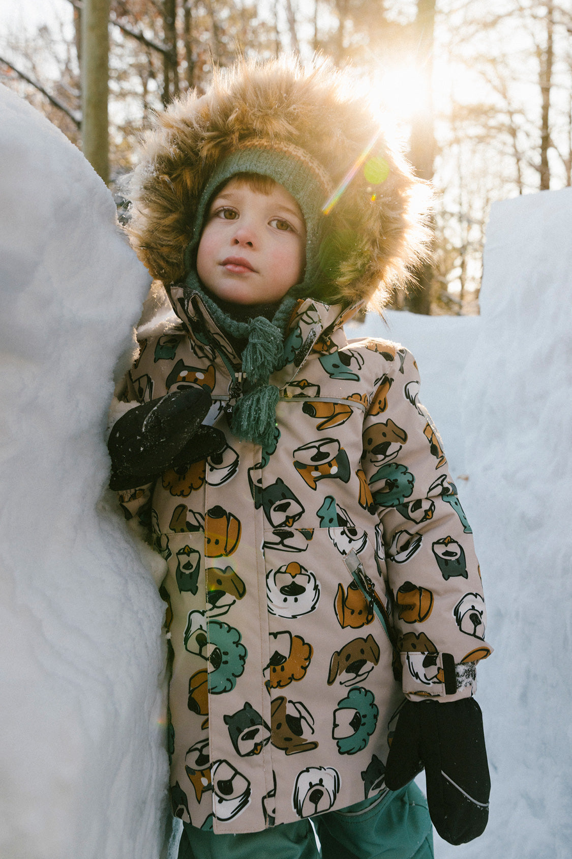 Child wearing the Deux par Deux DISCOVER snowsuit, beige with dog print, lifestyle view