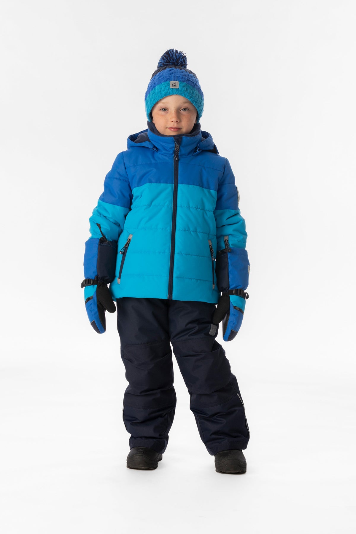 Child wearing the Deux par Deux PLAY snowsuit in light and dark blue, lookbook view 1