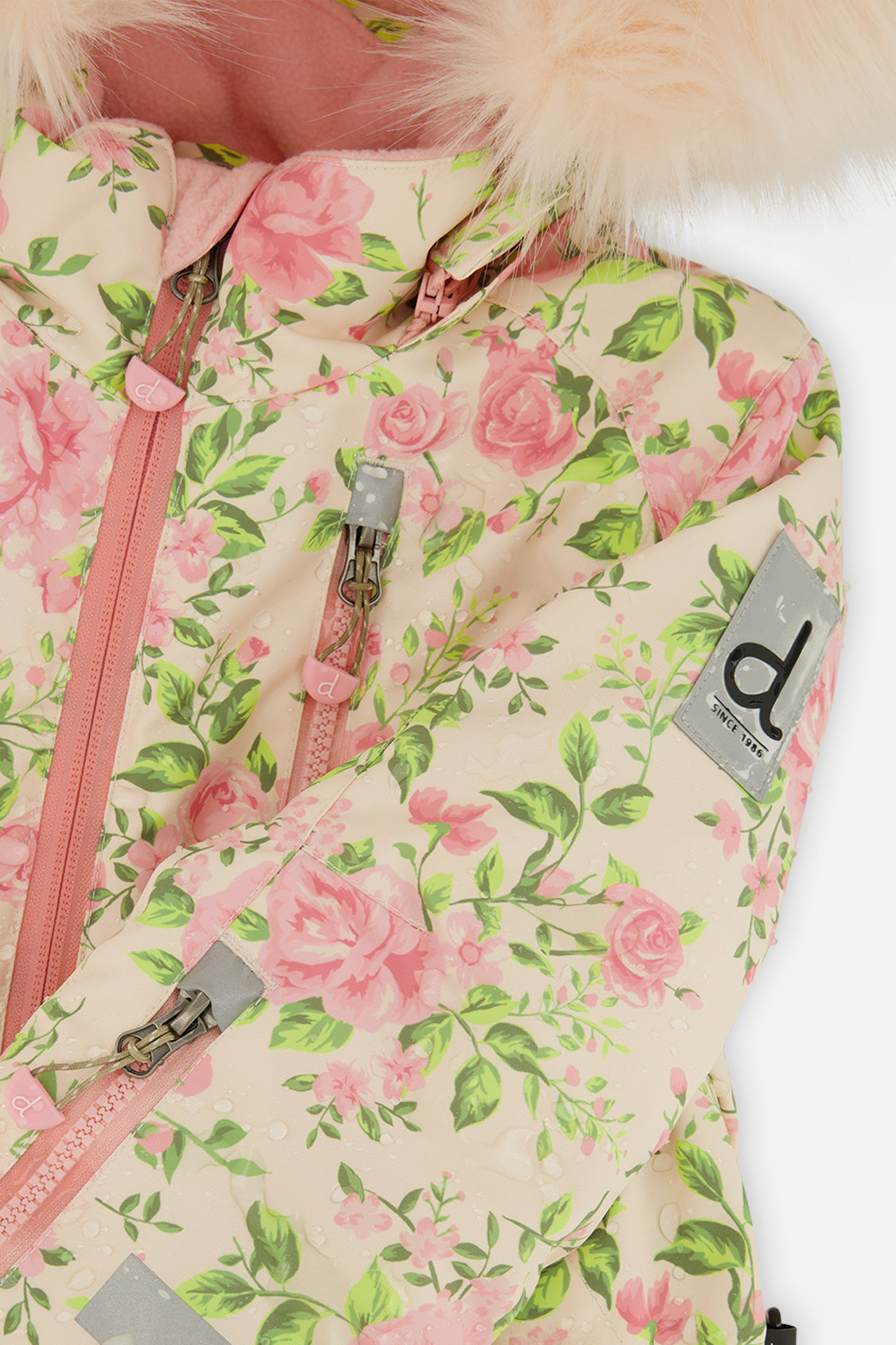 Close-up of the pink roses and green leaves on the beige Deux par Deux PLAY snowsuit with logo patch