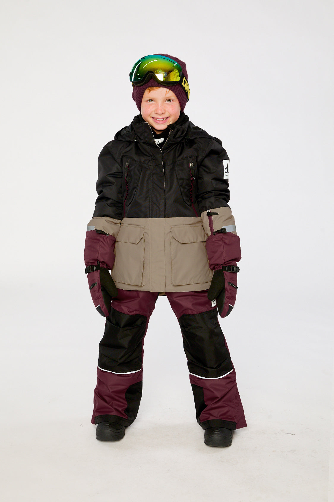 Child wearing the black, beige and burgundy Deux par Deux TEKNIK snowsuit, lookbook view