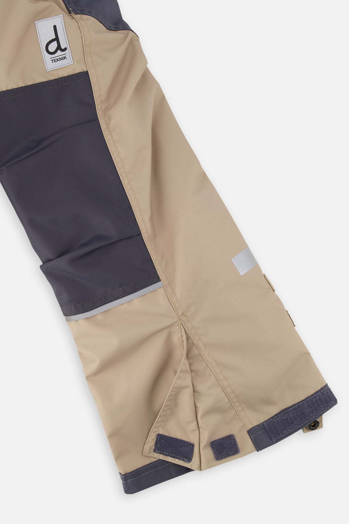 Close-up of the taupe and grey snow pants leg with reinforced panels and inner snow gaiter