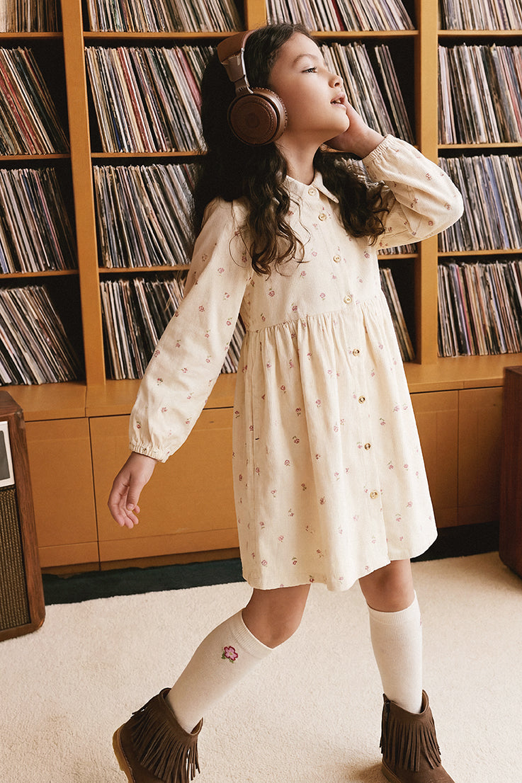 Child wearing the Deux par Deux beige floral corduroy shirt dress while listening to records