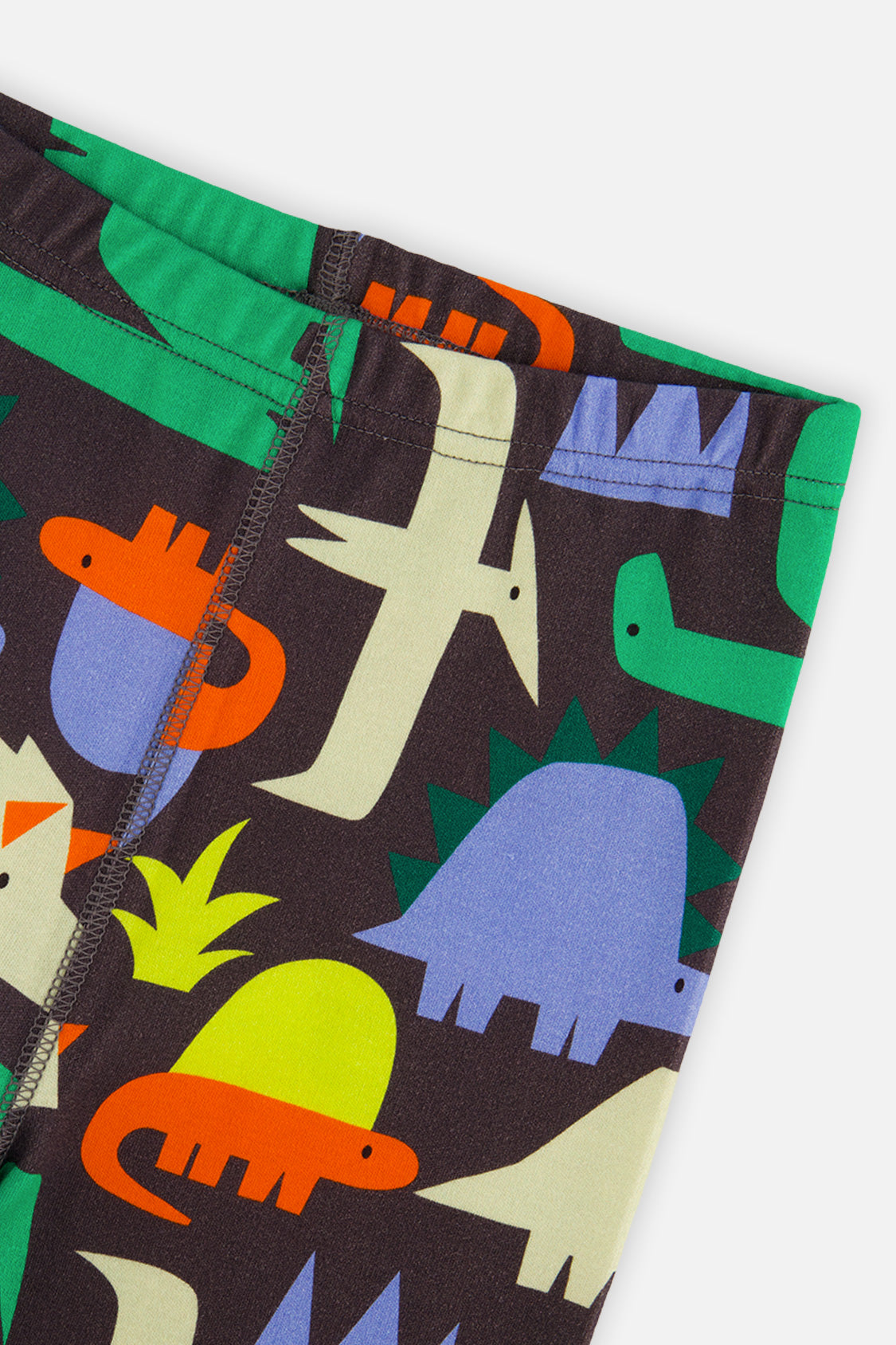Close-up of the pants waist and leg seam covered in green and blue and orange dinosaurs