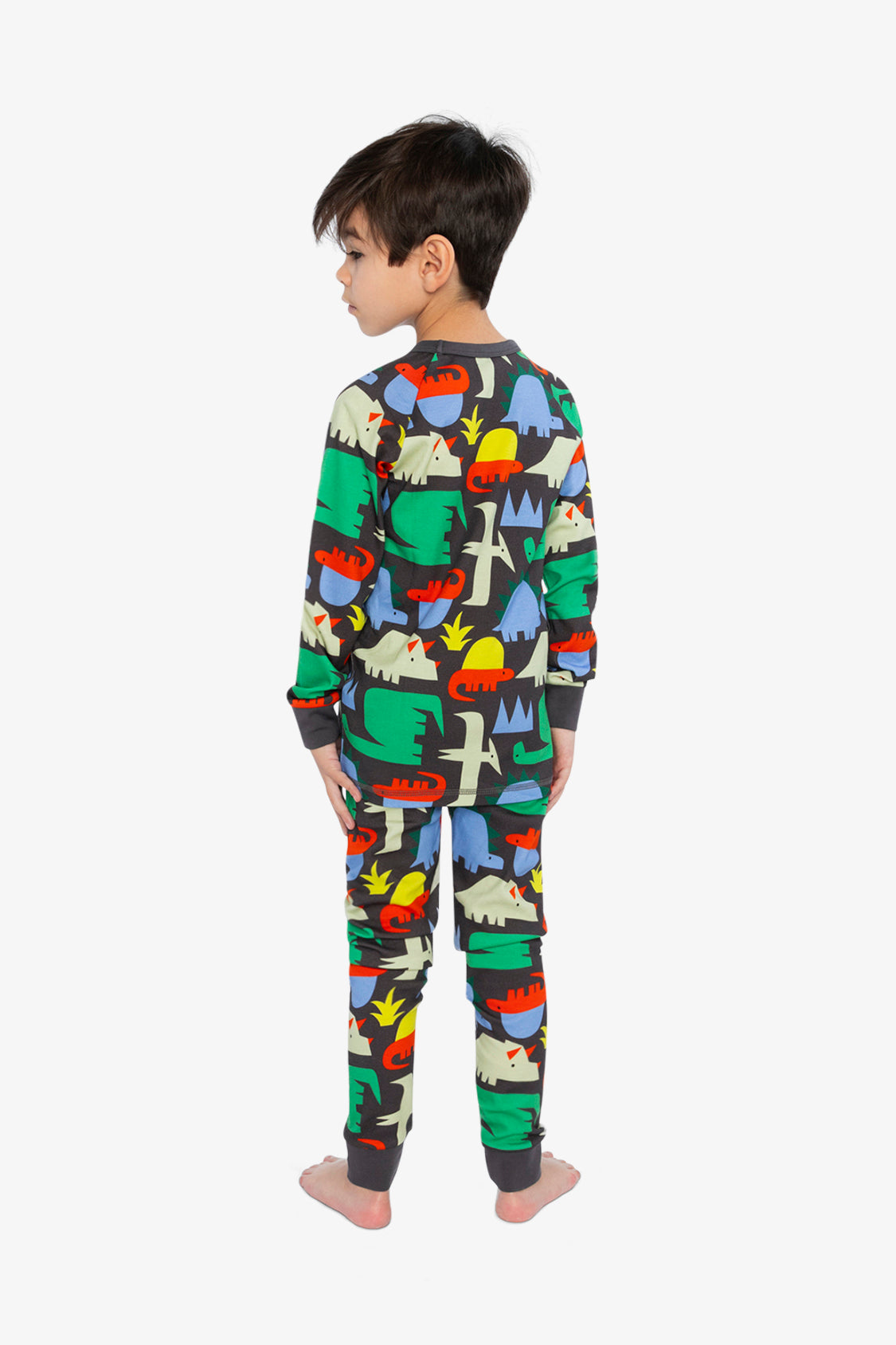 Child wearing the black dinosaur pajama set from behind with the head turned to the side
