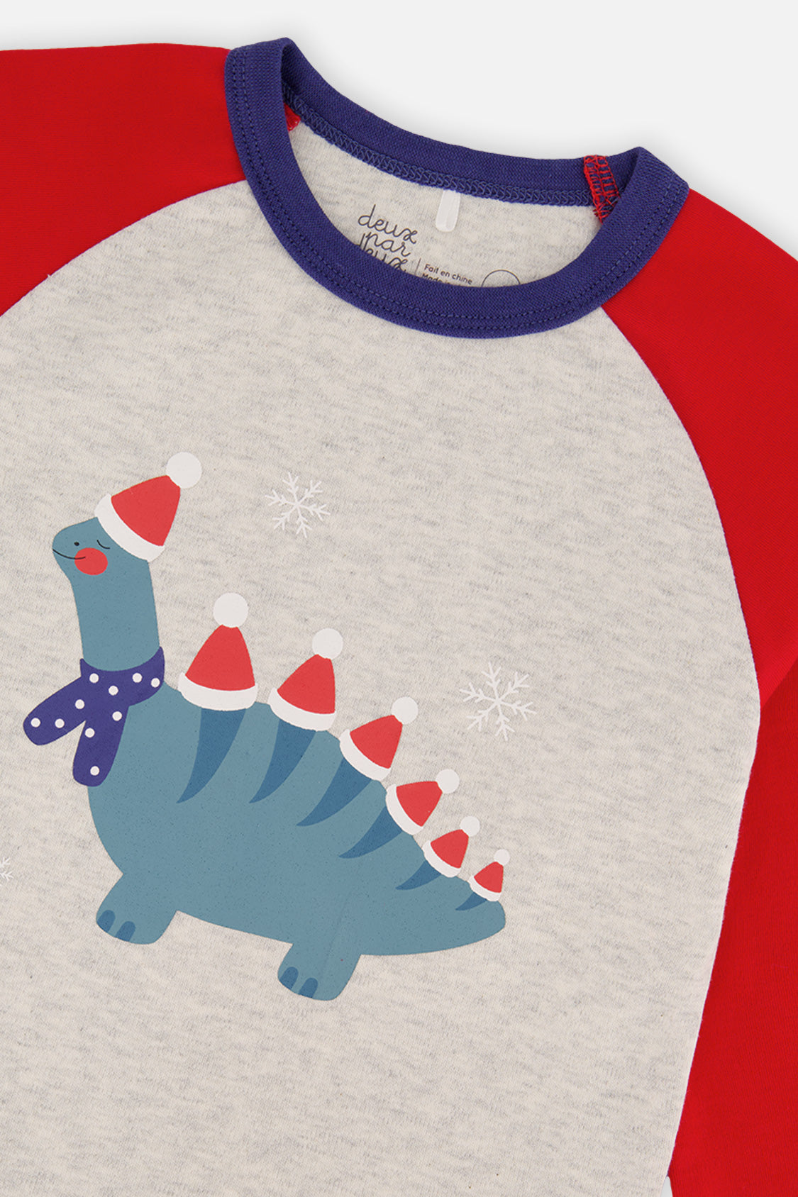 Close-up of the teal dinosaur in Santa hats and a purple scarf on the oatmeal top with the navy neckband
