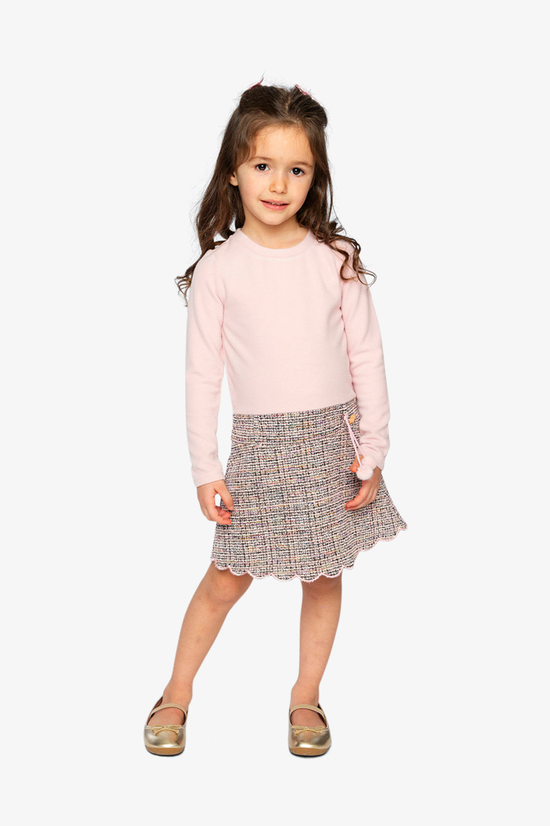 Child wearing the pink and black knit dress with a scalloped skirt hem, front view