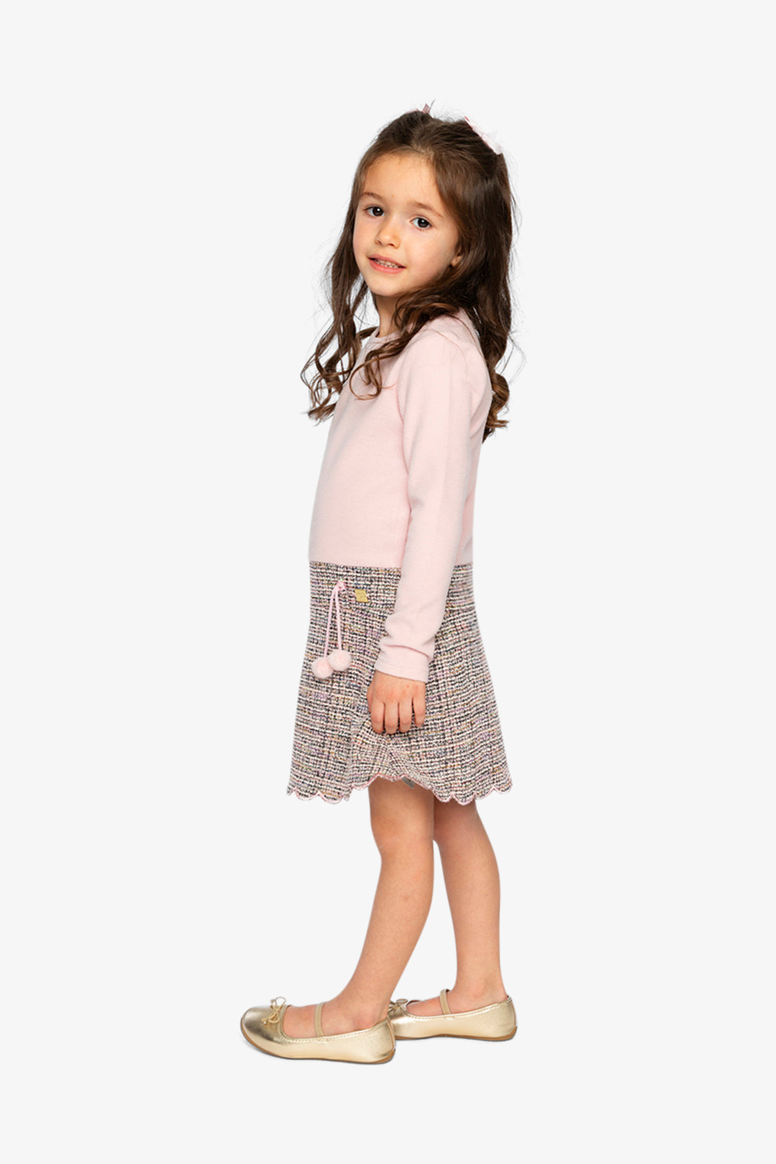 Child wearing the pink and black knit dress, side view