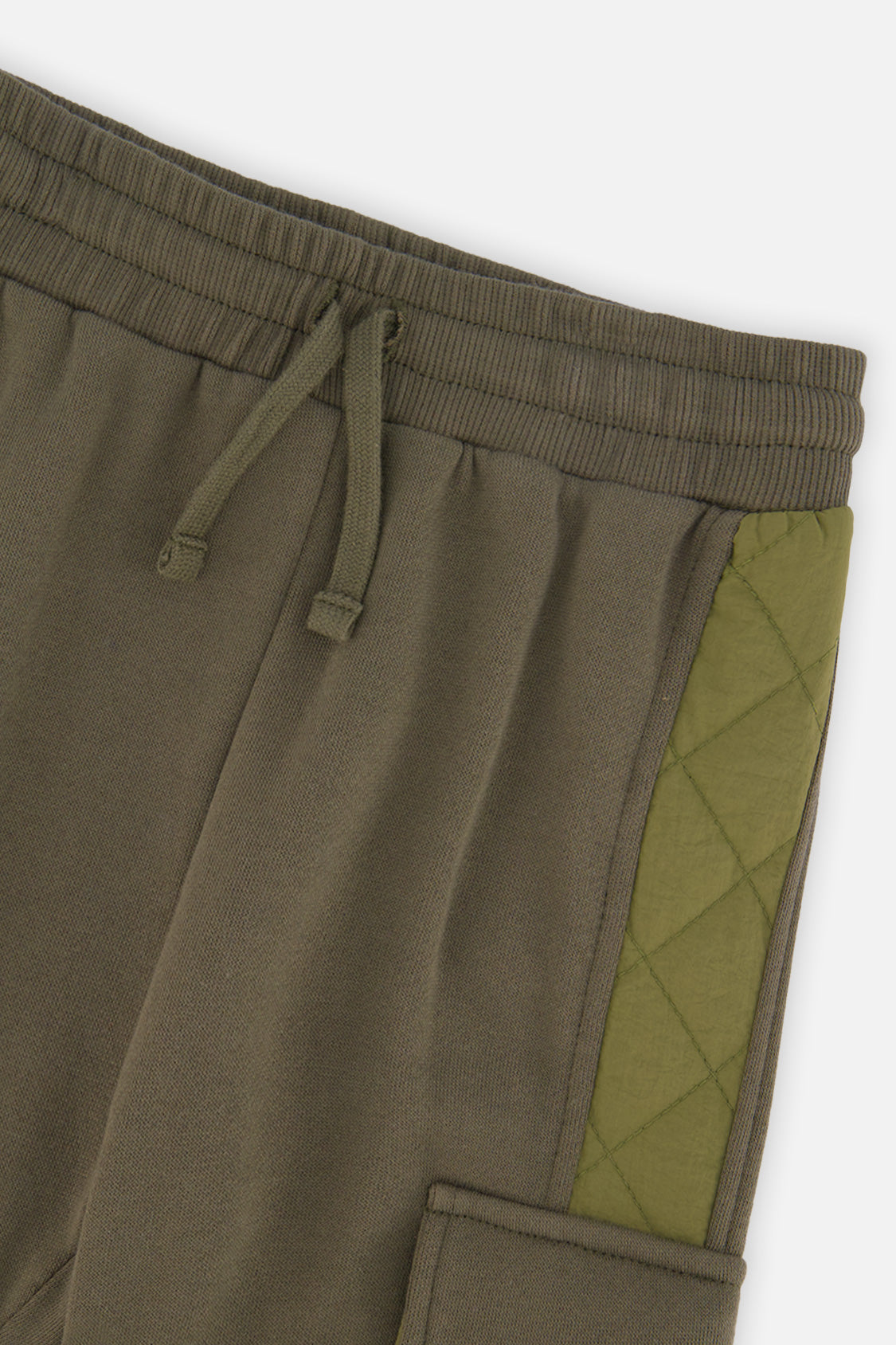 Close-up of the elastic drawstring waistband and quilted side panel on the green cargo sweatpants