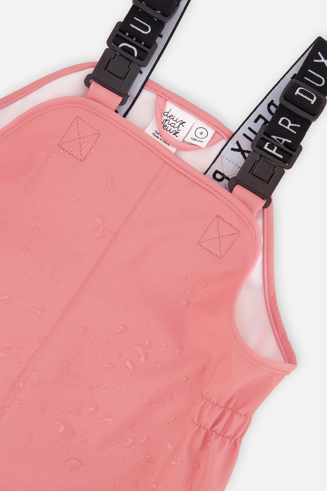 Close-up of the bib and elastic side panels on the pink Deux par Deux rain overalls
