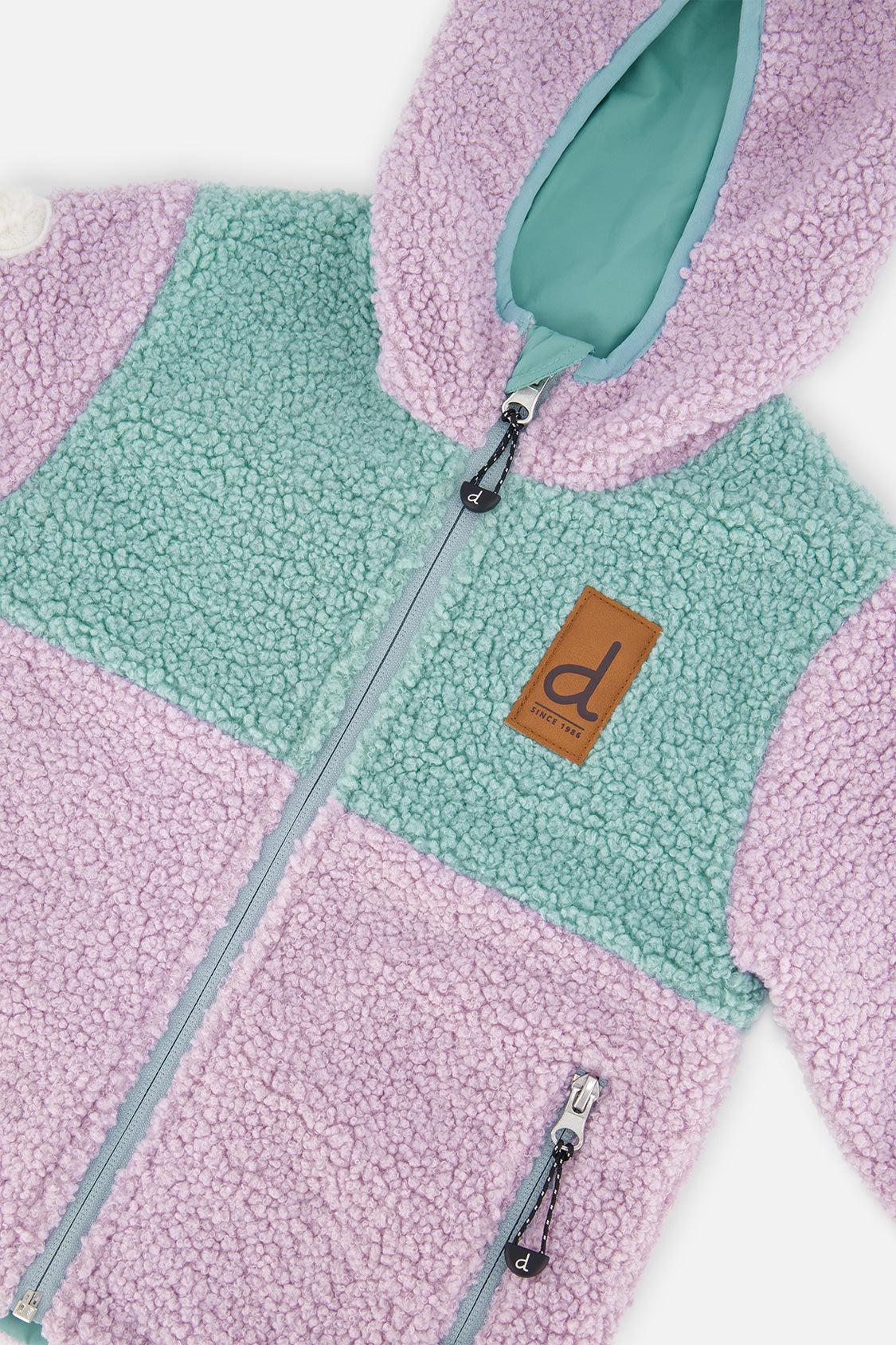 Close-up of the sherpa front, zipper and brown tag on the Deux par Deux reversible jacket