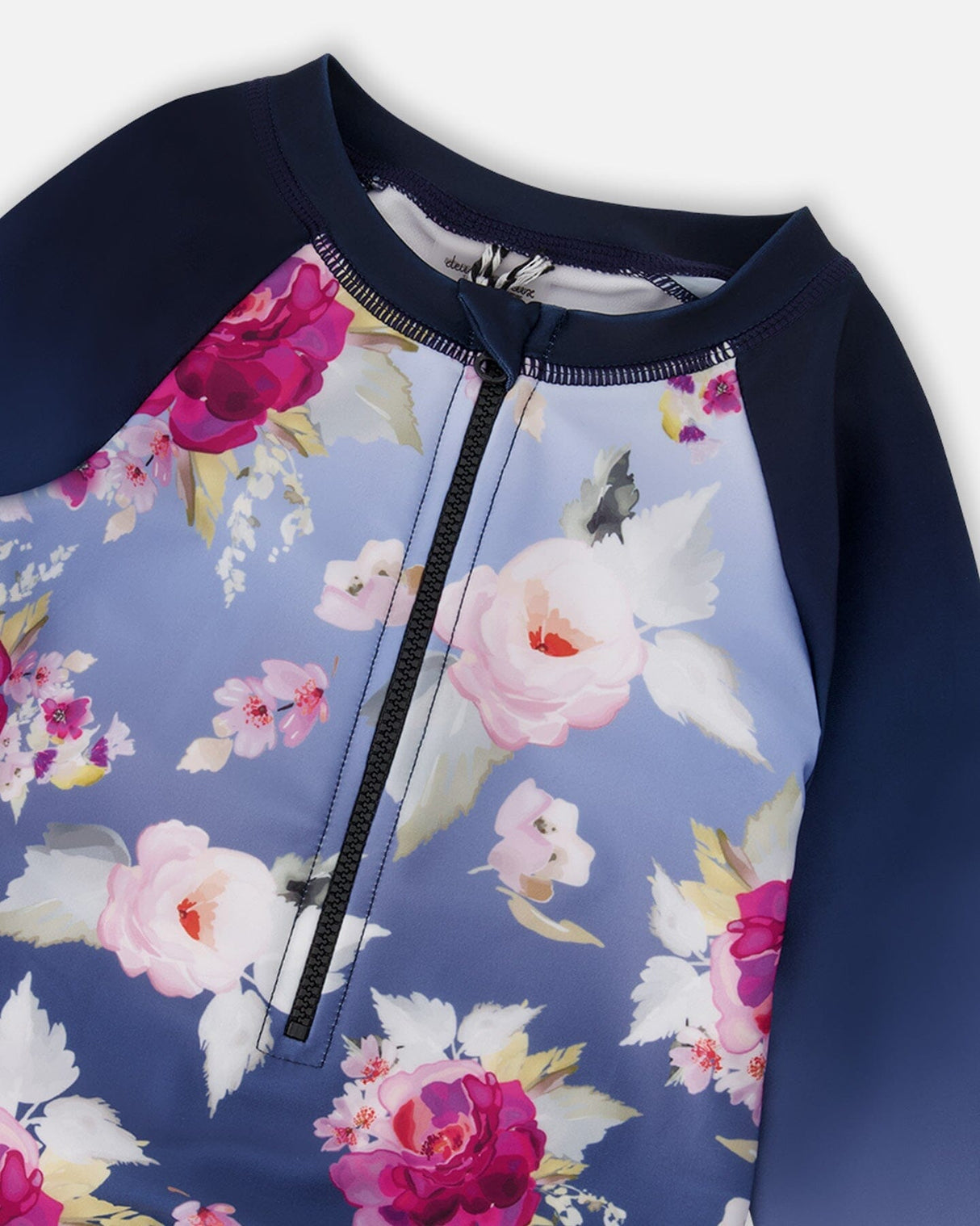 Close-up of rose print body and gradient blue sleeves on girl rashguard swimsuit