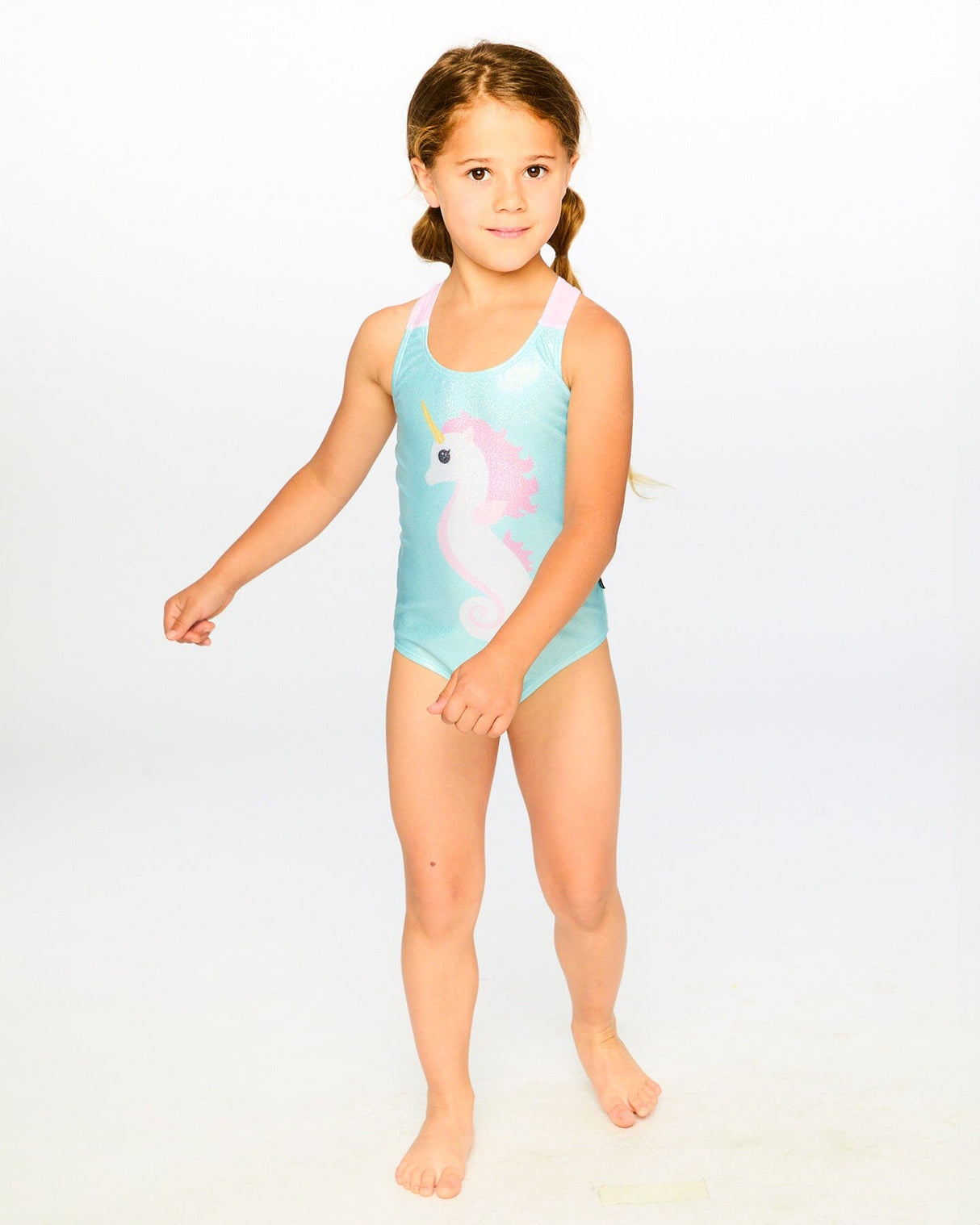Studio full-body view of girl in aqua seahorse one-piece swimsuit