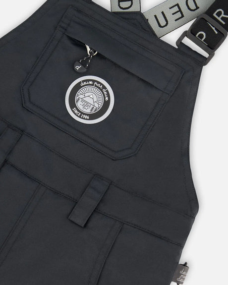Closeup of Cordura® reinforced black bib overall with logo patch.