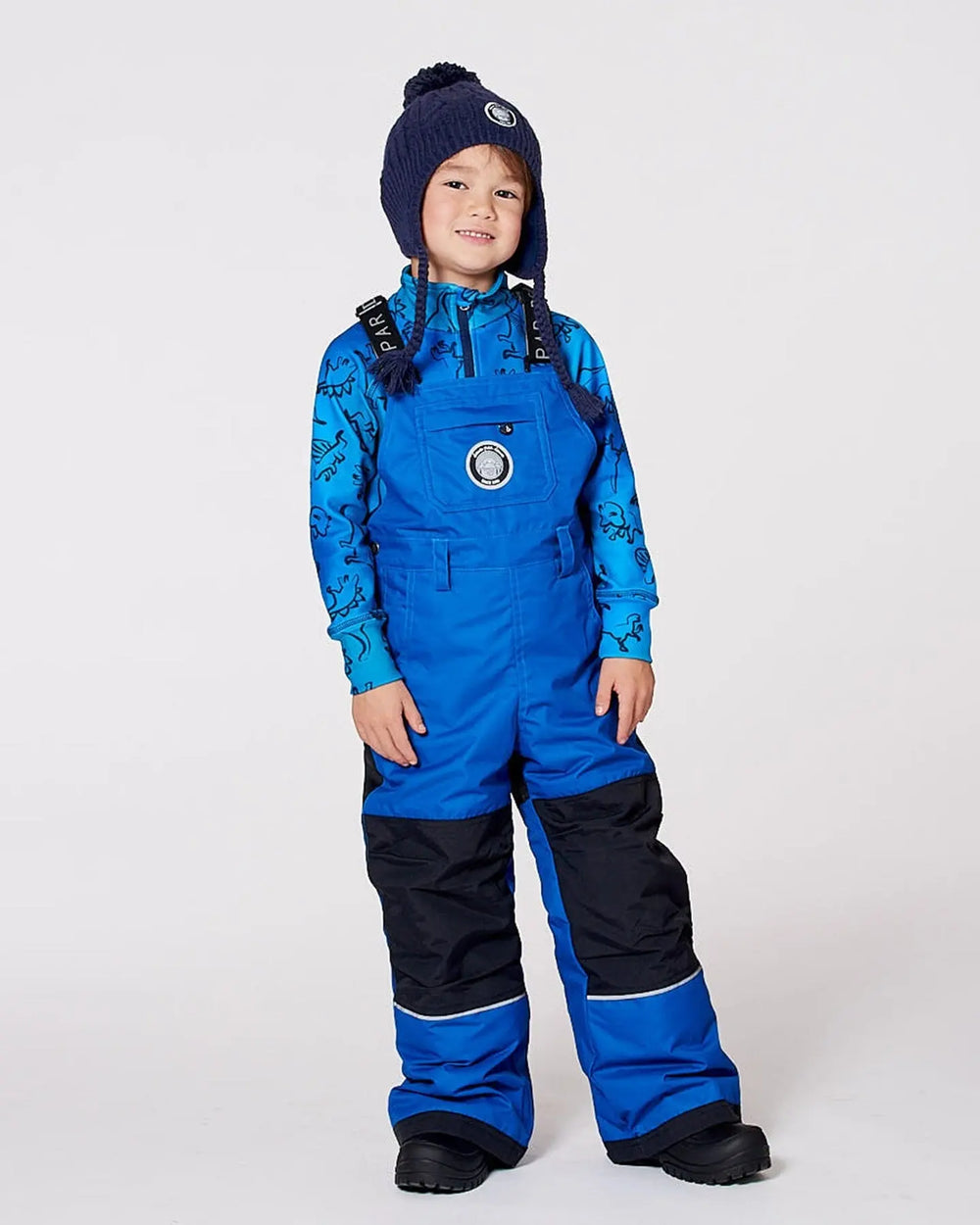 Boy wearing blue insulated snow bib overalls with suspenders.