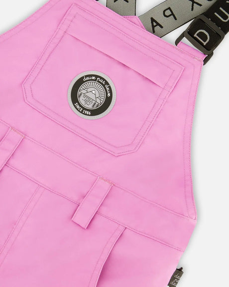 Closeup of bib chest pocket and strap hardware on waterproof, breathable fabric.