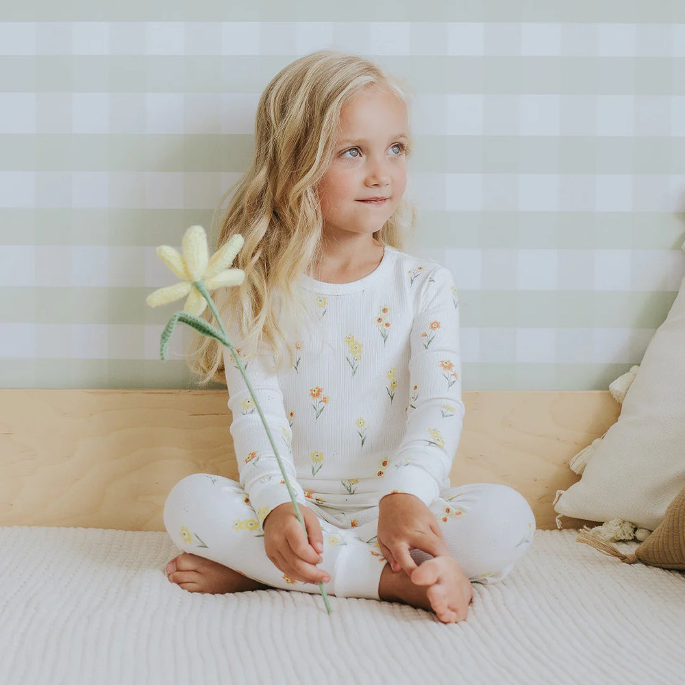 Toddler wearing off-white daffodil floral organic cotton pajama set by Petit Lem