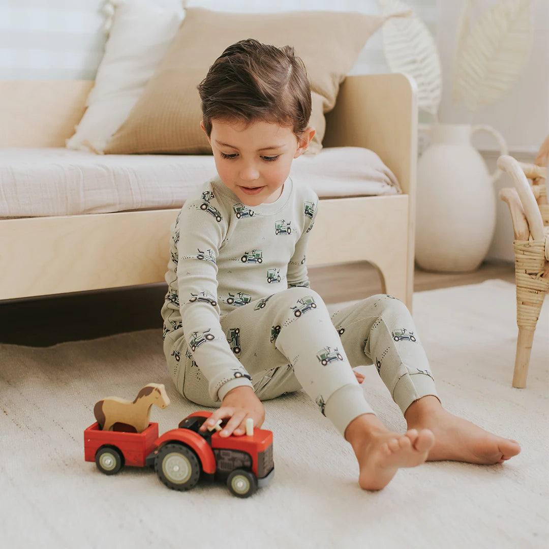 Toddler wearing tea green lawnmower print organic cotton pajama set by Petit Lem