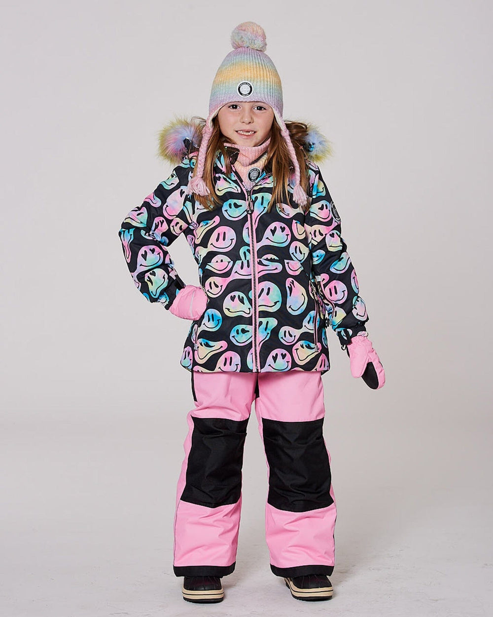 Model in two-piece ski suit pink bib pants, smiley jacket hood up — almost gone