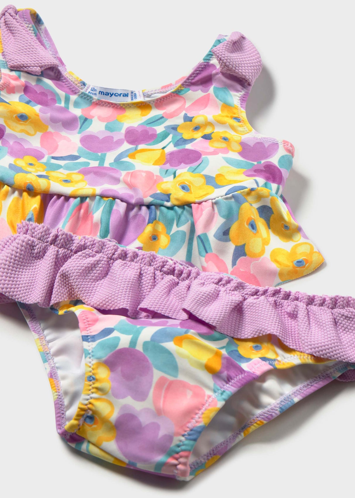 Closeup of Mayoral baby girl swim set showing Lilac ruffle trim, floral print, and stretch fabric.