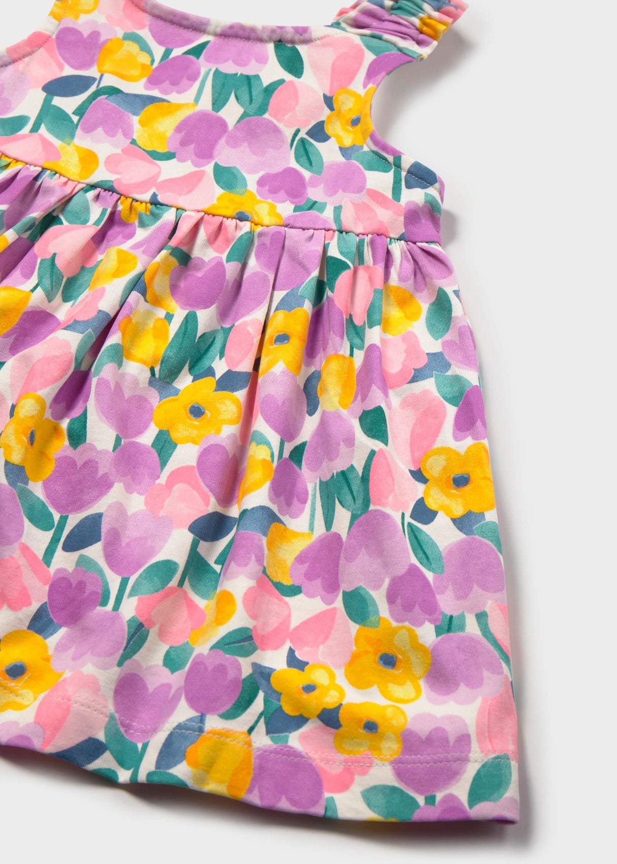 Closeup of Mayoral floral baby dress showing colorful print, gathered waist, and cotton stretch texture.