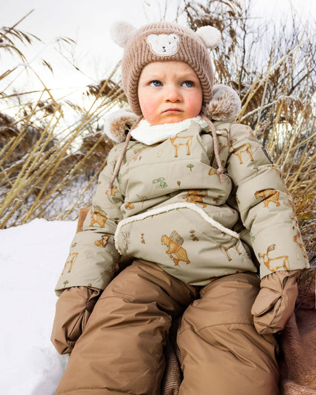 Lifestyle photo of a toddler wearing the Chanterelle Baby Snug snowsuit outdoors
