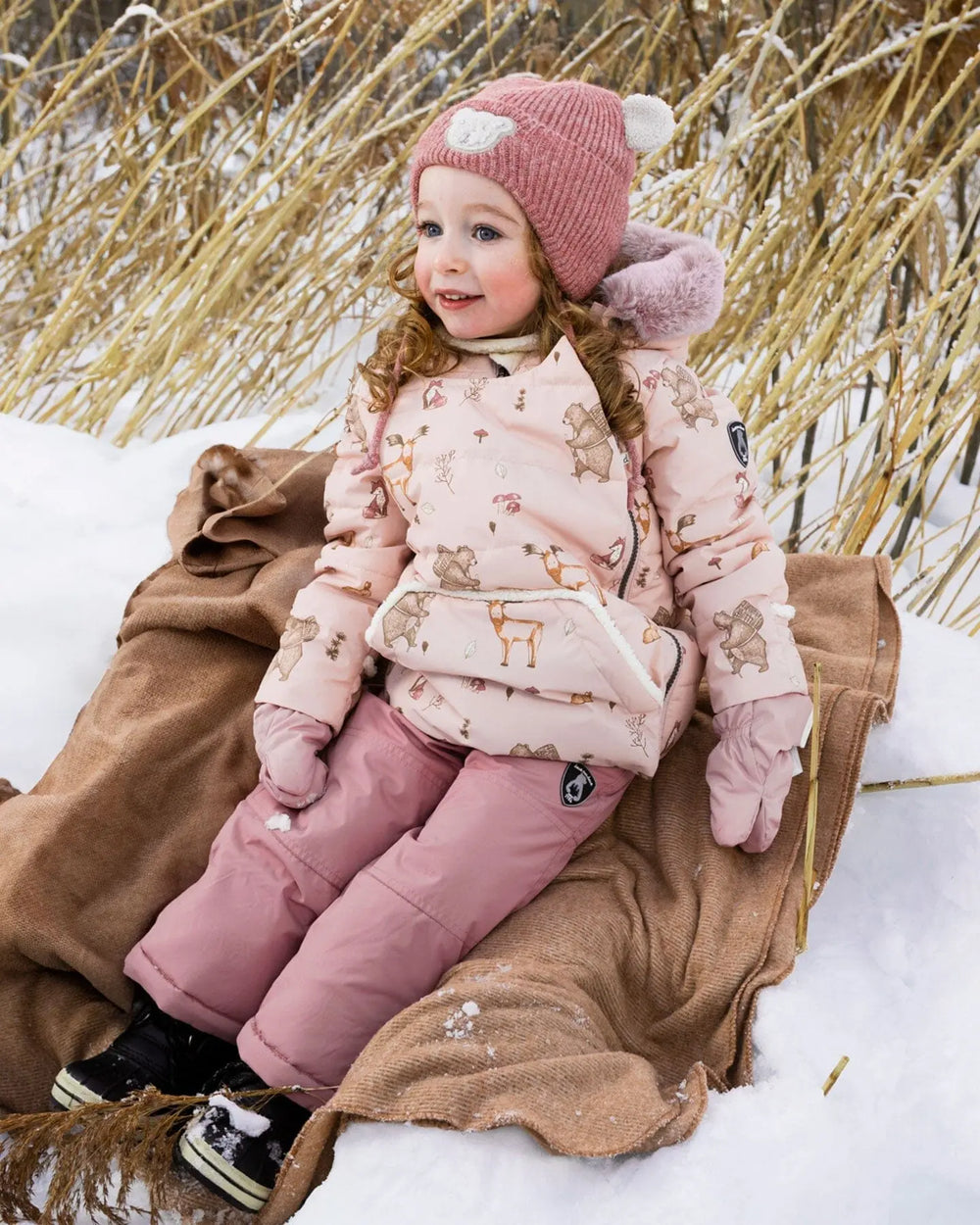 Toddler wearing Deux par Deux Baby Snug snowsuit in dusty pink