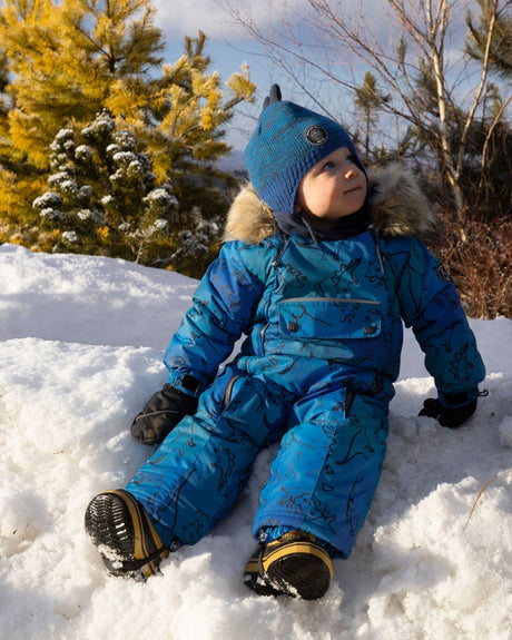 Lifestyle photo of toddler wearing the Deux par Deux blue dinosaur snowsuit outdoors