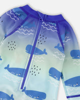 Detail shot of zipper, neckline, and whale pattern on blue rashguard swimsuit
