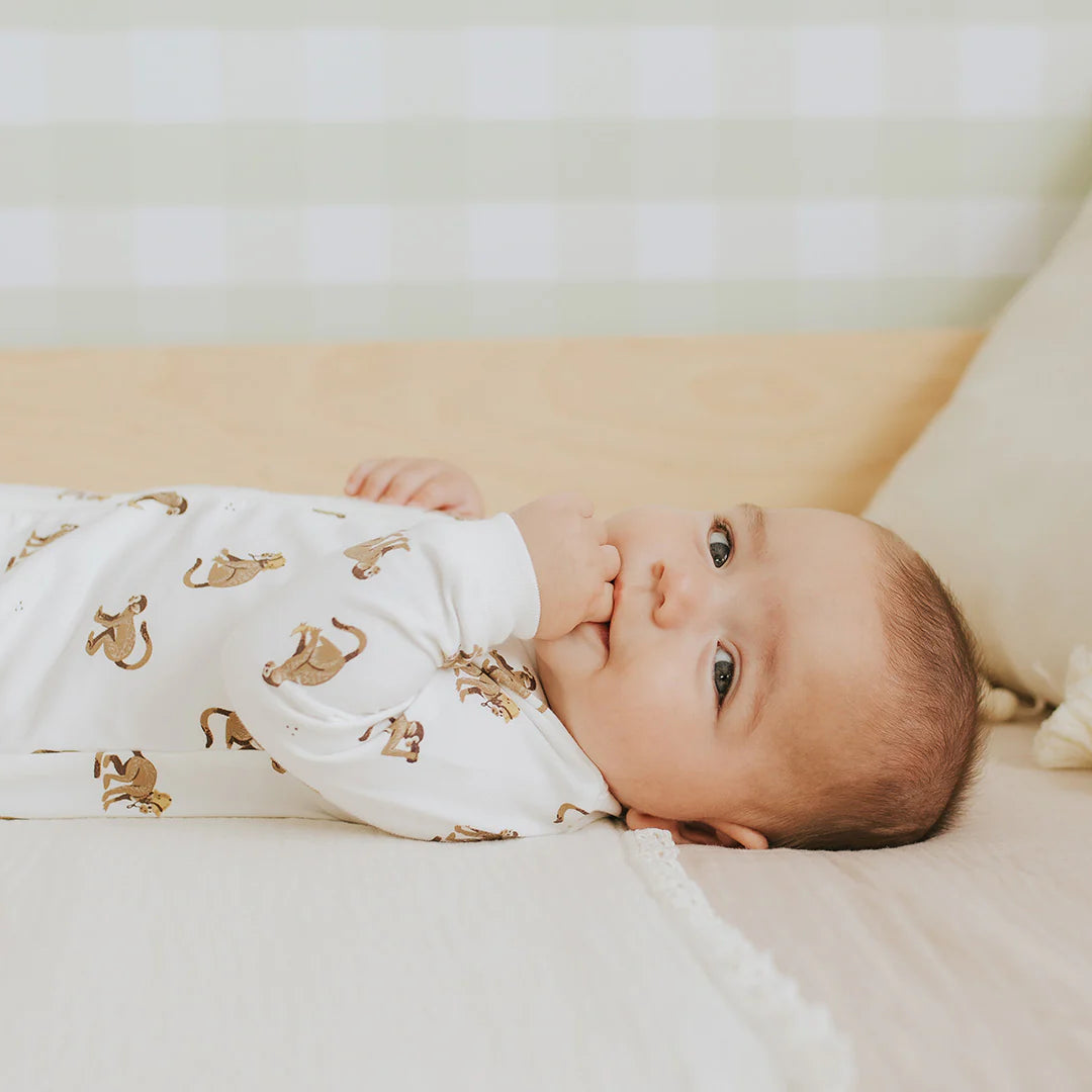 Baby in organic cotton monkey print sleeper with ribbed cuffs