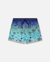 Front flat lay of Deux par Deux boy blue beach boys swim trunks with palm-tree print