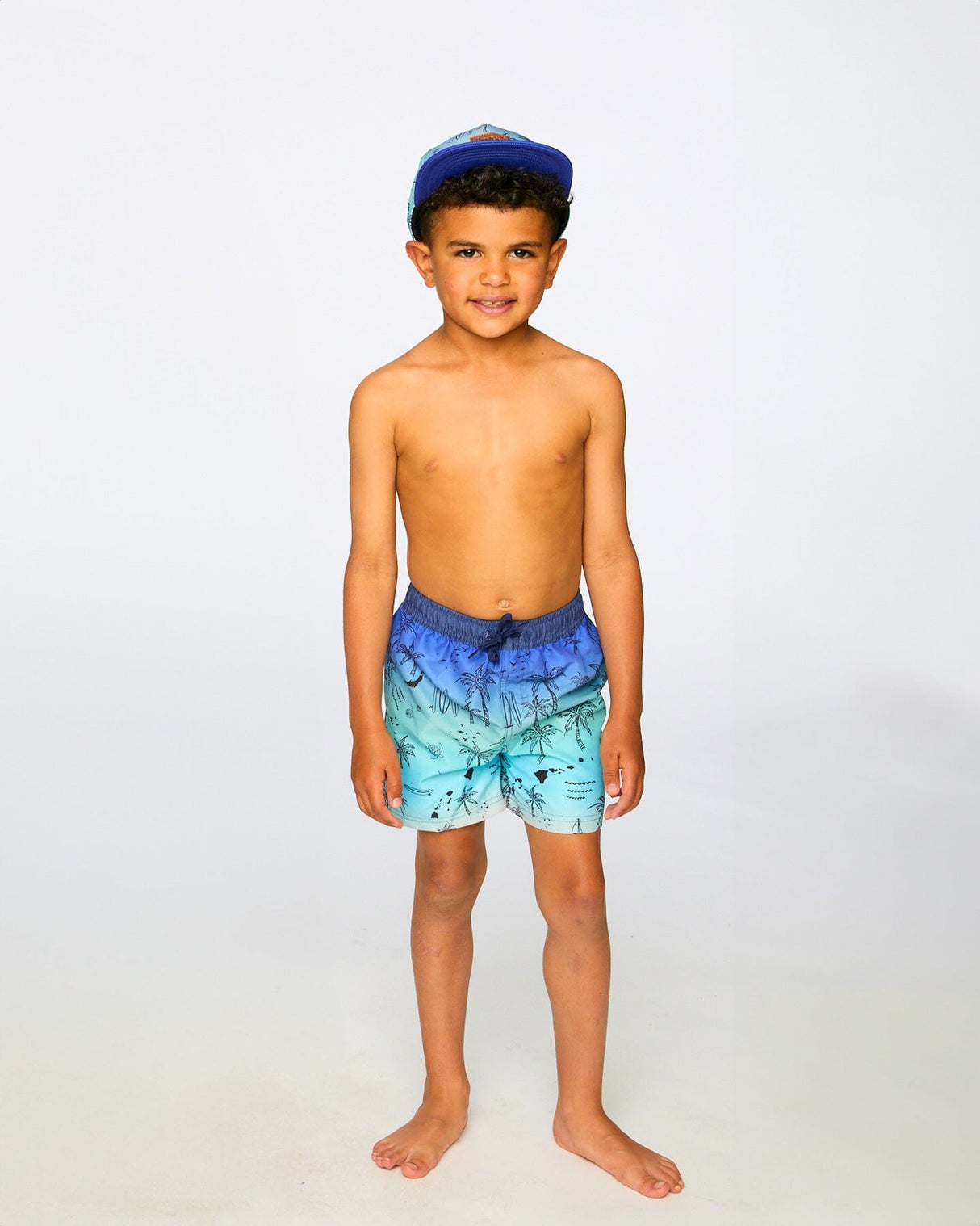 Boy in studio wearing blue beach print swim shorts front view