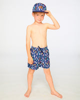 Boy standing in studio in navy surfboard swim shorts above the knee