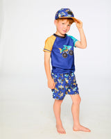Studio front view of boy in blue monster truck swim shorts