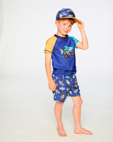 Studio front view of boy in blue monster truck swim shorts