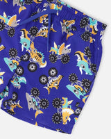 Close-up of waistband, drawstring, and monster truck with dinosaur print on blue swim shorts