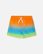 Front flat lay of Deux par Deux baby and boy boardshorts in orange blue green gradient