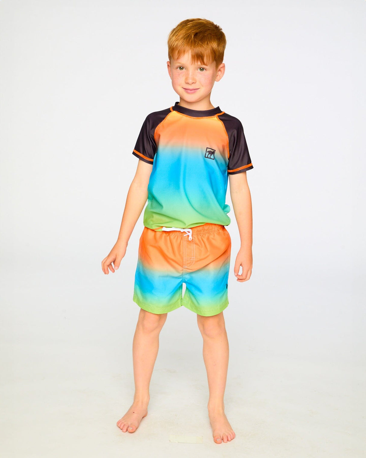 Boy wearing gradient boys swim trunks and rashguard, standing front view