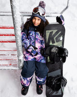 Girl wearing the pink & blue marble one-piece snowsuit — front view on snow with hood up