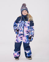 Girl wearing the pink & blue marble one-piece snowsuit — front view showing fit through hood and legs