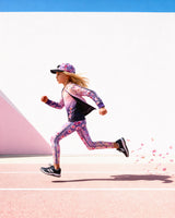 Child wearing the Deux par Deux reversible cardigan in pink to mauve gradient with floral sleeves, mid-stride outdoors