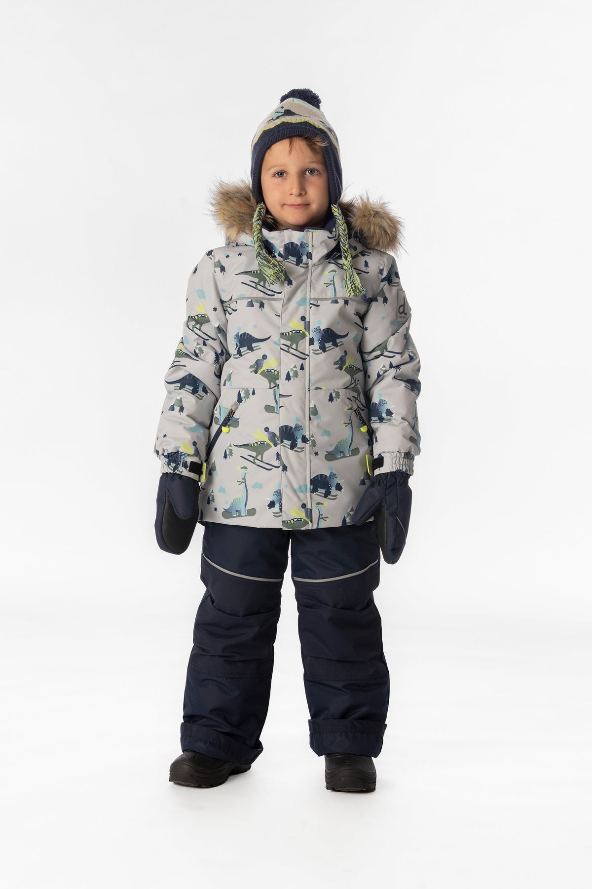 Child wearing the Deux par Deux DISCOVER snowsuit in grey skiing dinosaur print, lookbook view 1