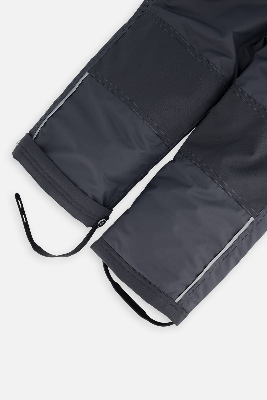 Close-up of the charcoal CHILL snow pant leg with adjustable foot strap and reflective trim