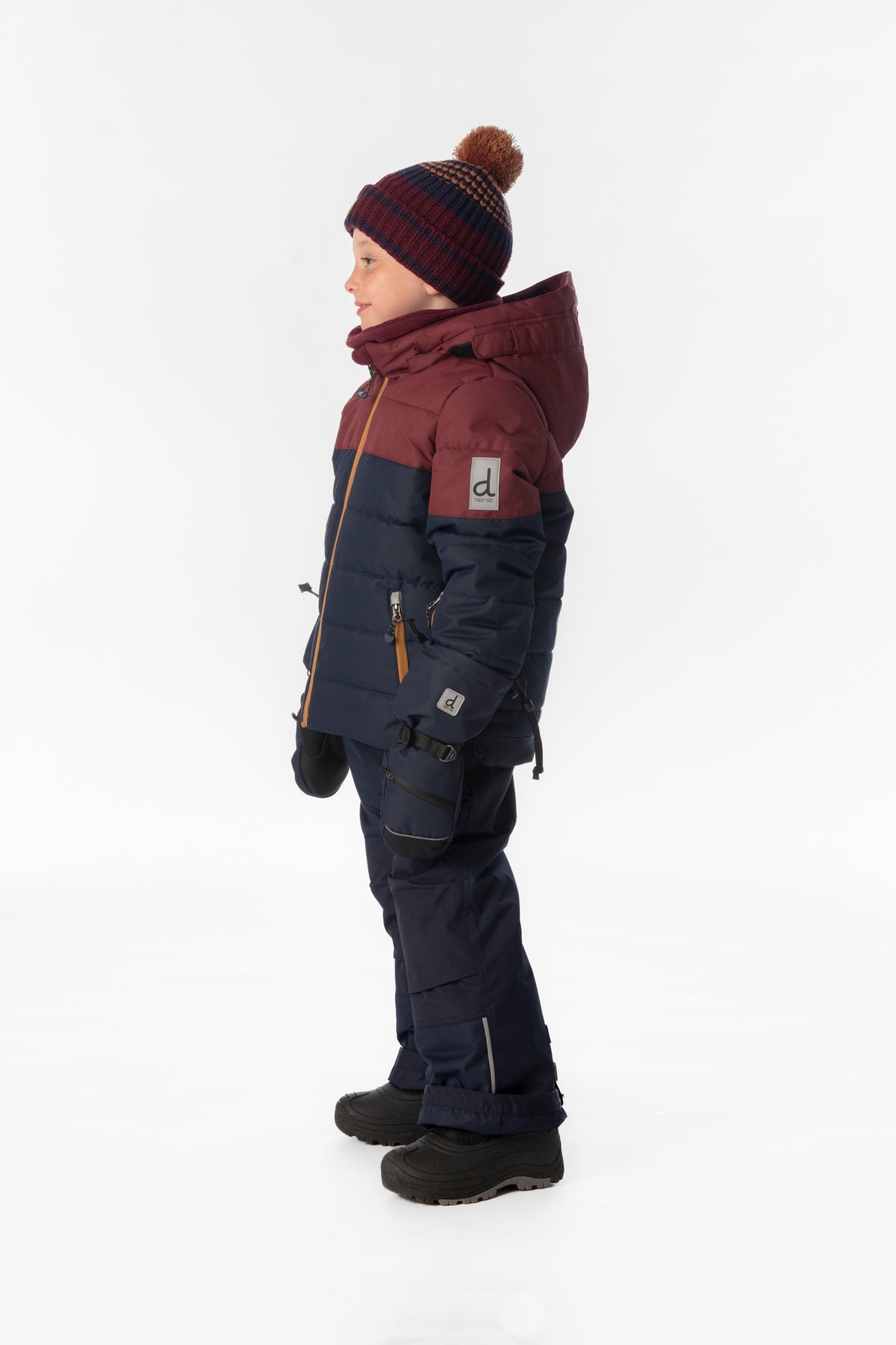 Child wearing the Deux par Deux PLAY snowsuit in navy and burgundy, lookbook view 2