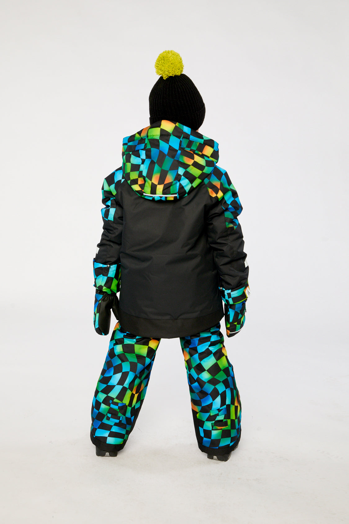 Child in the black and checkerboard PLAY snowsuit, back view