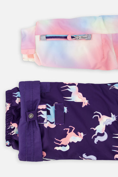 Close-up of the PLAY jacket sleeve ski-pass pocket and the adjustable unicorn-print pant hem