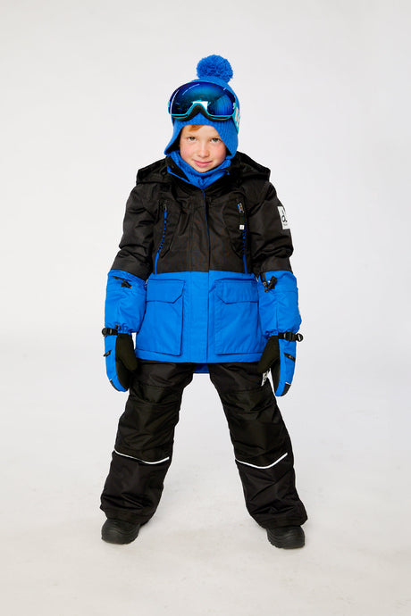 Child wearing the Deux par Deux TEKNIK snowsuit in royal blue and red, winter lookbook